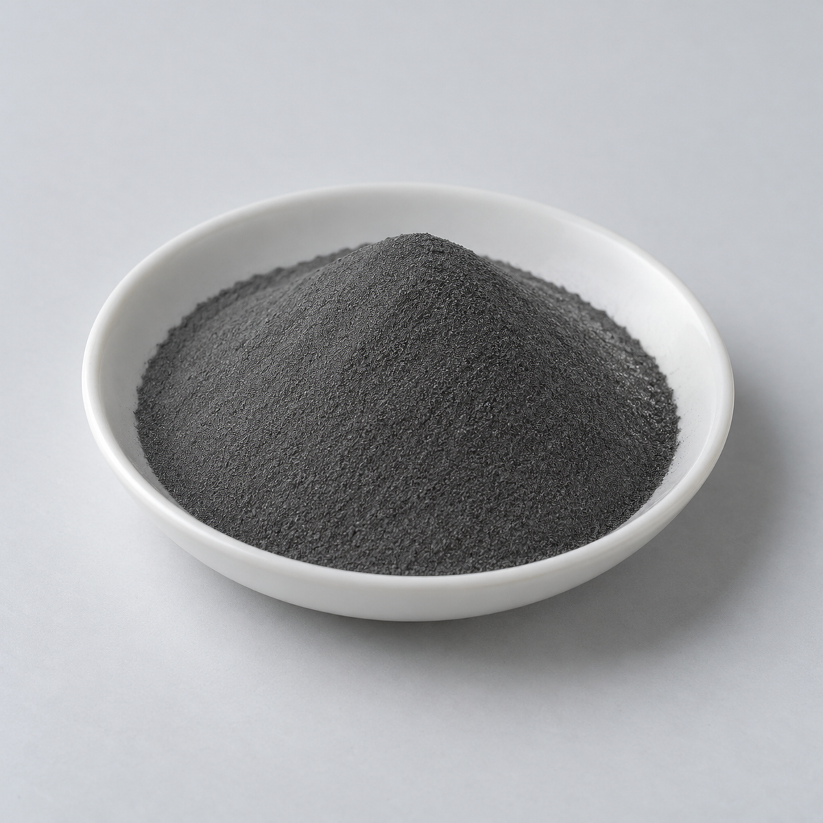 Representative image of 304L Stainless Steel Spherical Powder: fine dark-gray 304L stainless steel powder in a white dish
